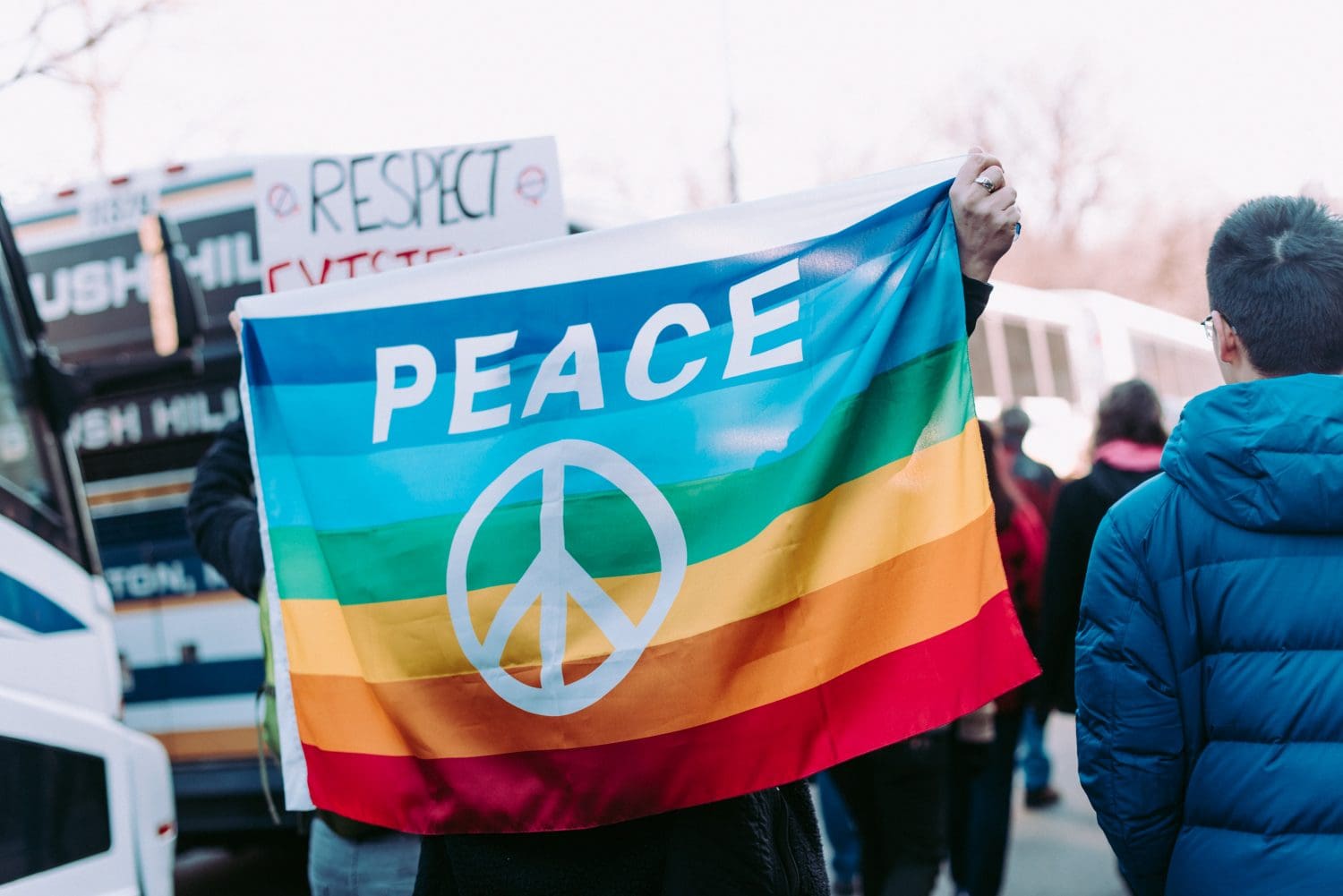 Person holding rainbow flag with Peace Sign