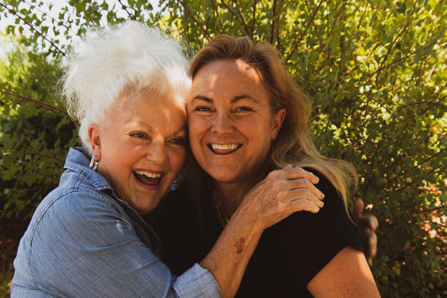 Two Women, one with white hair, one with brown hair in an embrace