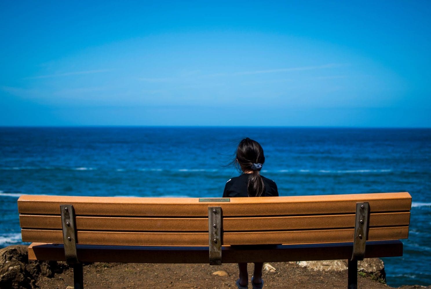 Woman sitting on bench overlooking a large body of water