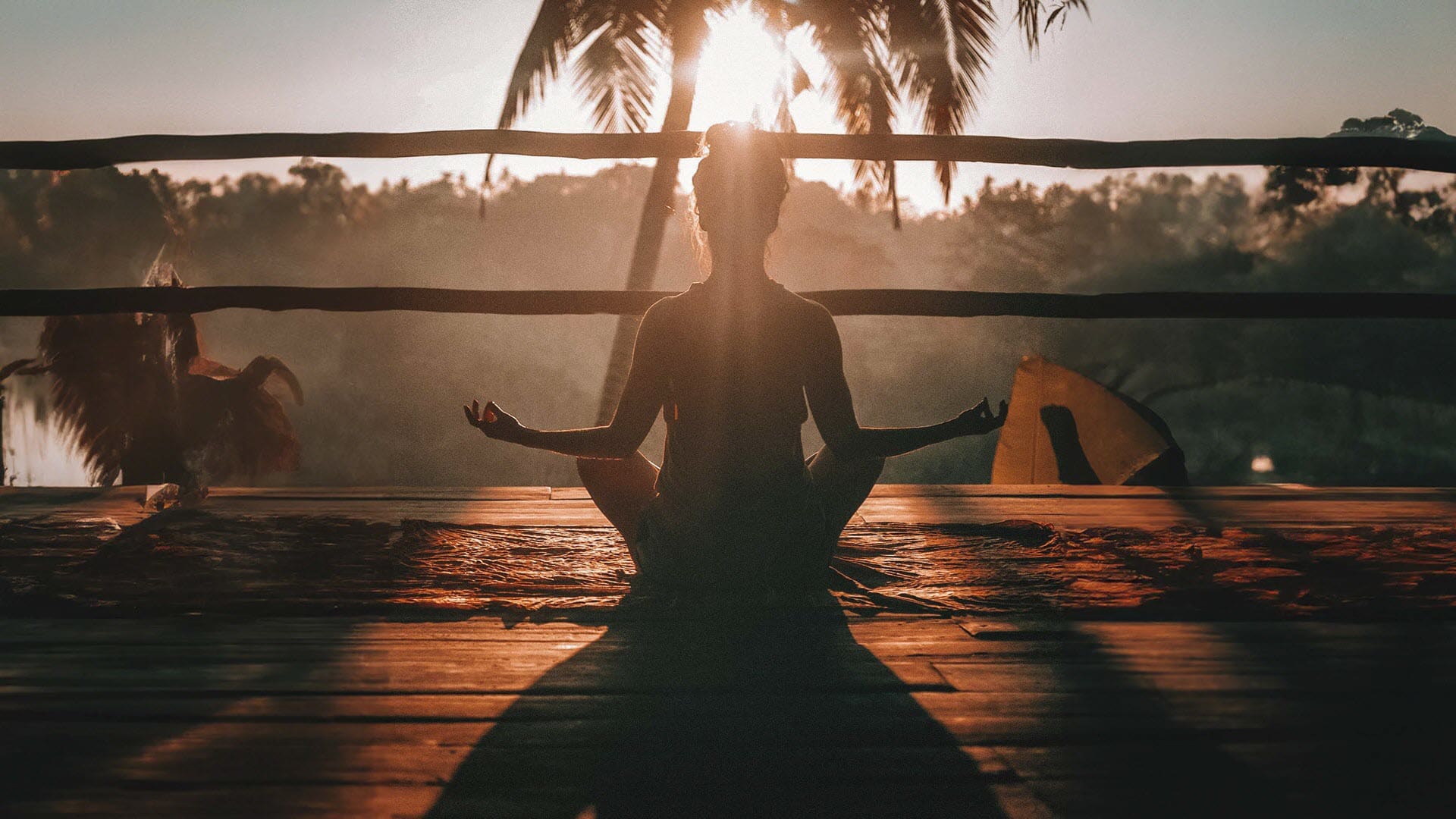 Woman meditating on porch in morning sunlight