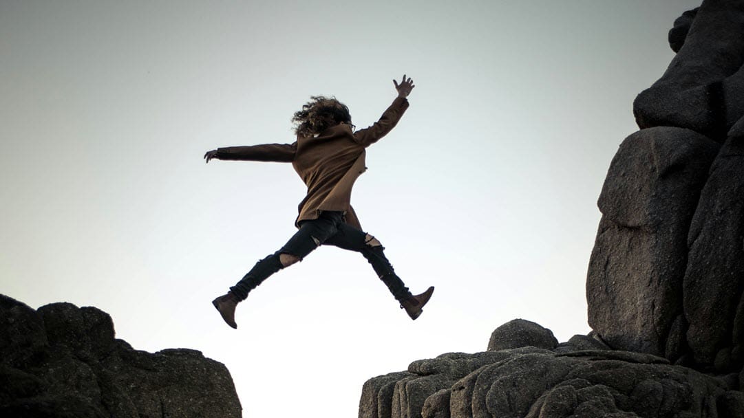 Woman jumping from one rock to another